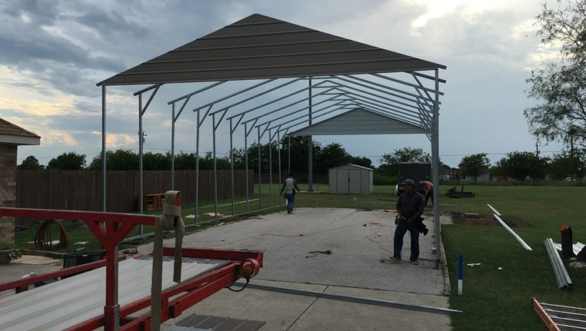 Crew building a double wide metal garage structure.