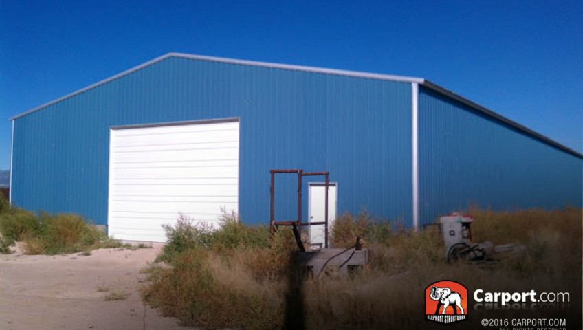 50x100x14 Commercial metal garage building 50 x 100 with blue walls and white trim, one roll up garage door and walk in door.