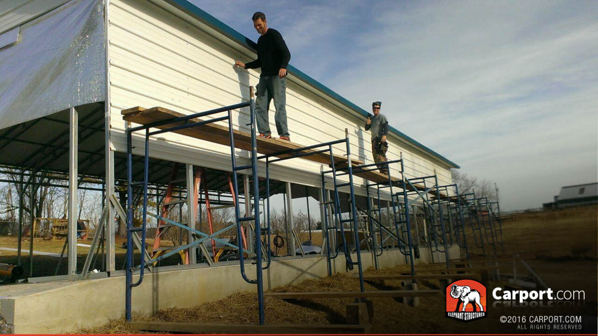 Crew standing on scaffolding with carport during installation.