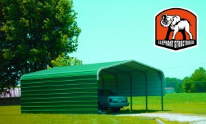 Green carport with half wall on one side and one wall on the other.