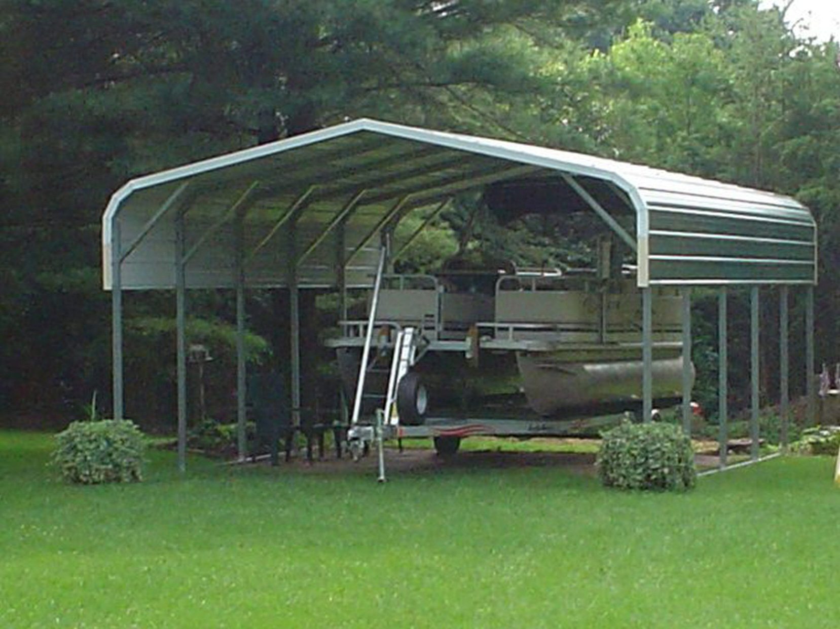 Green pontoon boat cover with pontoon boat parked underneath.